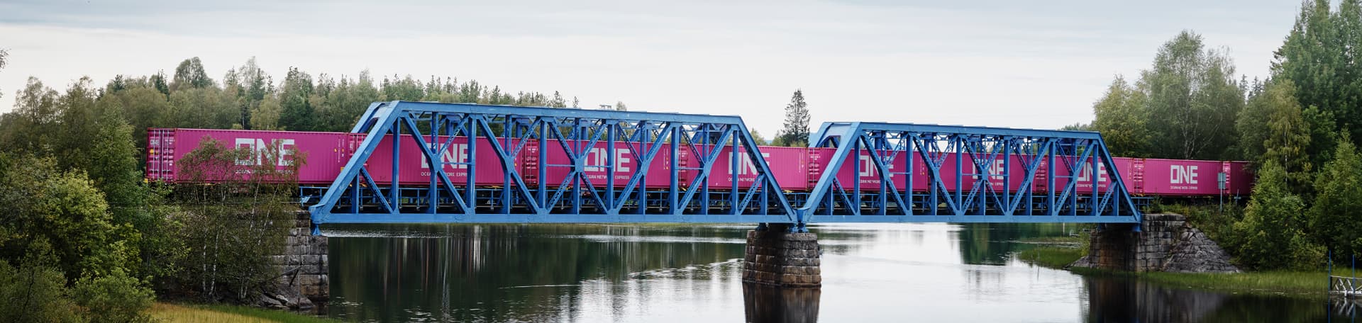 Green mobility freight train carrying ONE containers across bridge