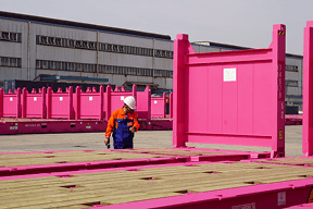 Worker wearing safety gear inspecting flat rack container